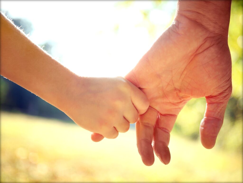 大人と子どもが手をつないで歩いている写真