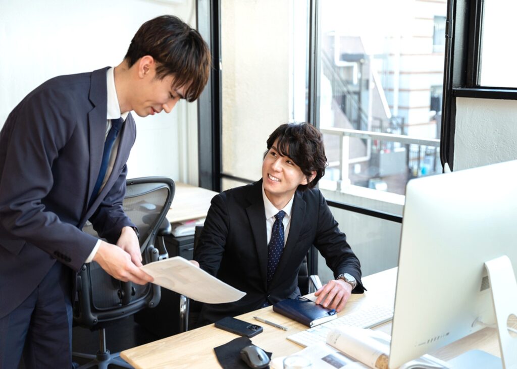 職場で上司と部下が資料を確認しながら穏やかに会話している様子