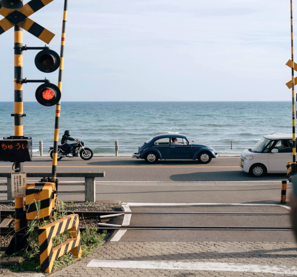 鎌倉の海沿いの踏切で車が行き交う穏やかな風景