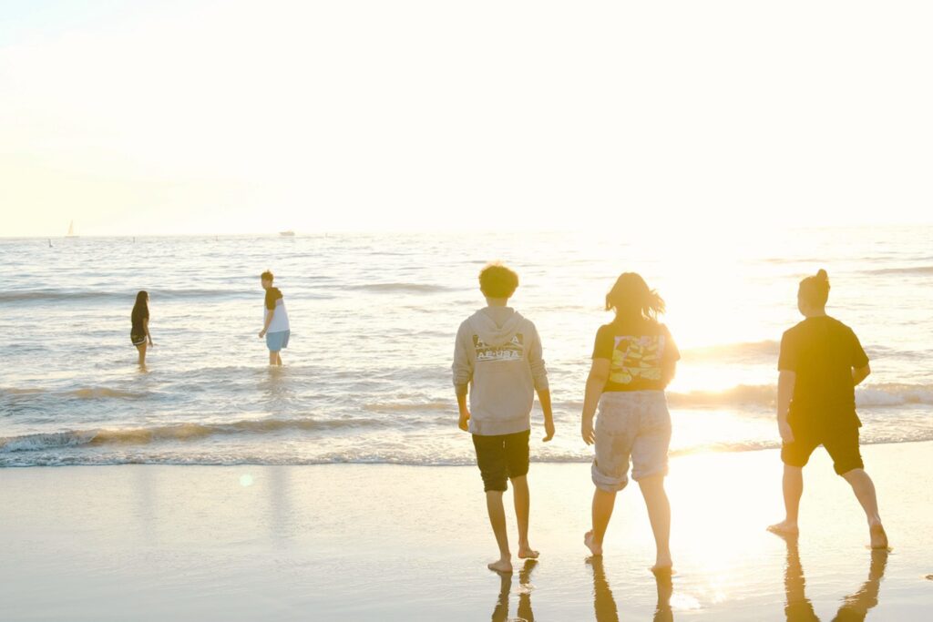 夕方の由比ヶ浜で海に入る人たちと光に包まれた風景