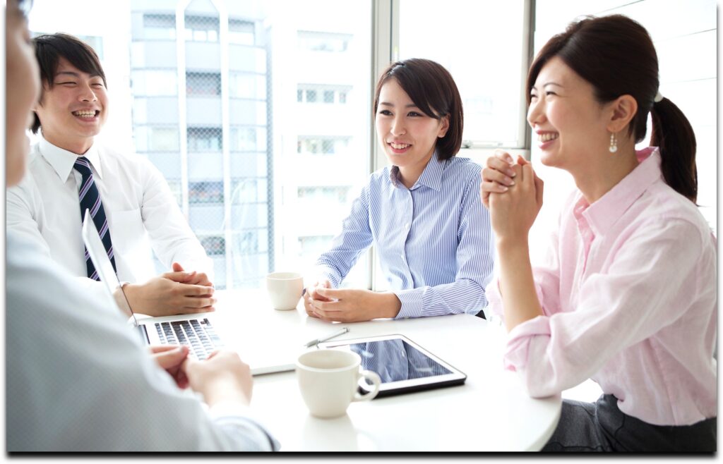 職場で自然な笑顔を交わしながら話し合うチーム