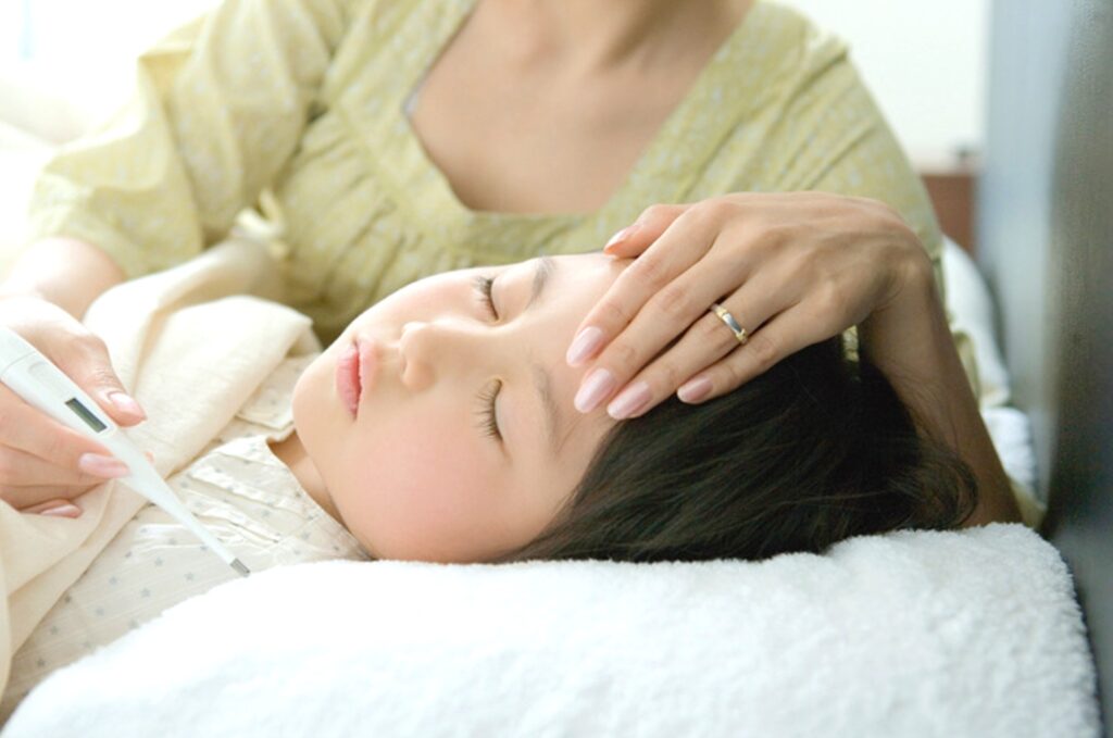 子どもの額に手を当てて体調を確認するお母さん