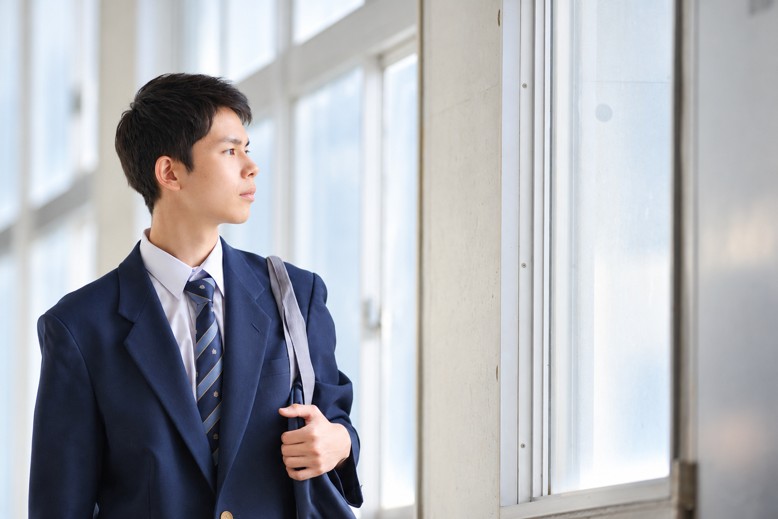 窓辺に立ち、外を見つめるスーツ姿の男性