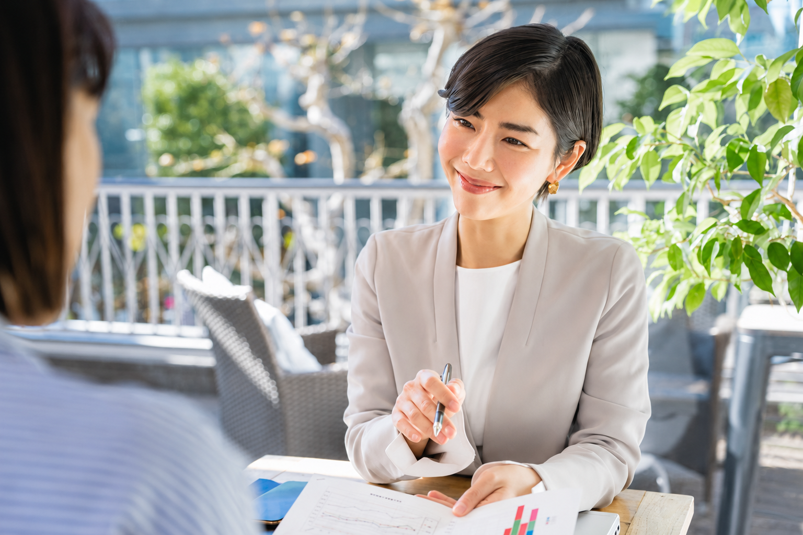 資料を前に、ペンを持ちながら相手の話に耳を傾ける女性